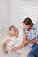 Young couple sitting on floor doing crossword