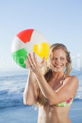 Gorgeous blonde in floral bikini holding beach ball