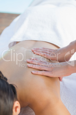 Calm brunette enjoying a massage poolside