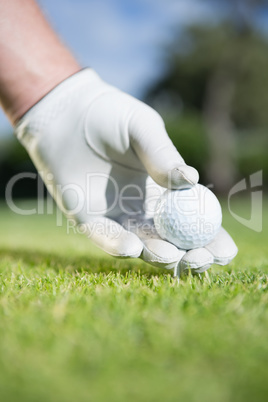 Golfer placing golf ball on tee