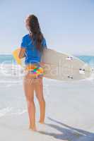 Fit surfer girl standing on the beach with her surfboard