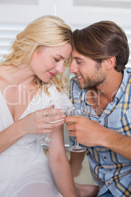 Cute young couple sitting on floor together having white wine