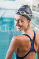 Pretty swimmer standing by the pool smiling at camera