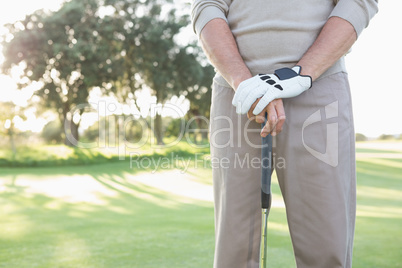 Mid section of golfer standing with club