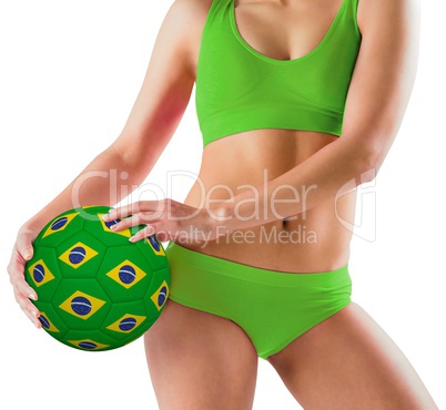 Fit girl in green bikini holding brazil ball