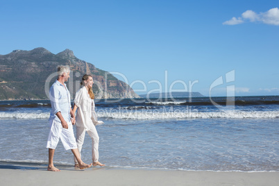 Happy couple walking barefoot on the beach