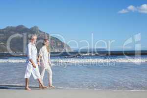 Happy couple walking barefoot on the beach