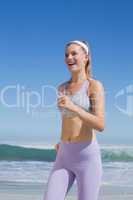 Sporty happy blonde jogging on the beach