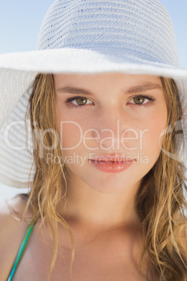 Beautiful girl on the beach smiling in white straw hat and bikin