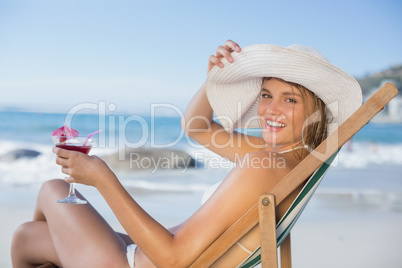 Smiling woman relaxing in deck chair with cocktail