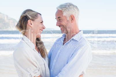 Happy couple hugging on the beach looking at each other