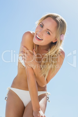 Beautiful blonde in white bikini smiling at camera on the beach