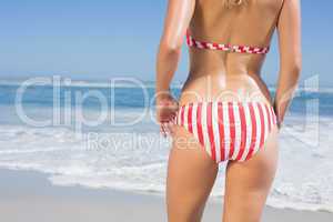 Mid section rear view of fit woman in striped bikini at beach