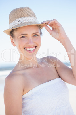 Pretty smiling blonde on the beach wearing straw hat