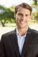 Handsome businessman in the park smiling at camera