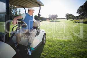 Golfer driving his golf buggy in reverse