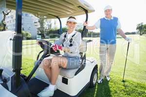 Happy golfing couple setting out for the day on buggy