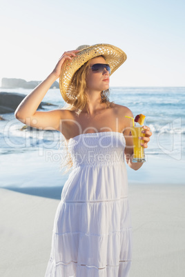 Beautiful blonde in white sundress on the beach with cocktail
