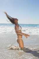 Beautiful woman in white bikini tossing wet hair
