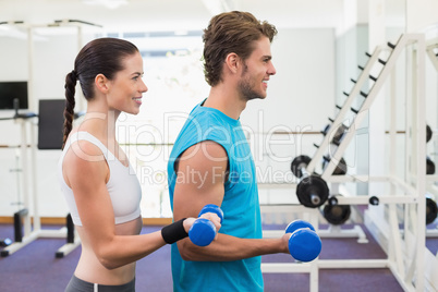 Fit couple exercising with blue dumbbells