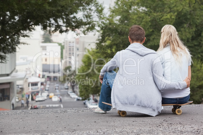 Cute young couple sitting on skateboard