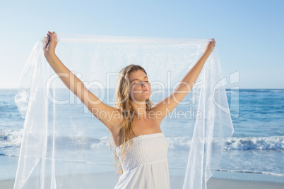 Beautiful calm blonde in white sundress on the beach with scarf