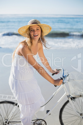 Beautiful blonde in white sundress on bike ride at the beach