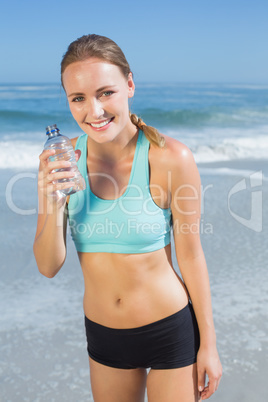 Fit woman standing on the beach taking a drink