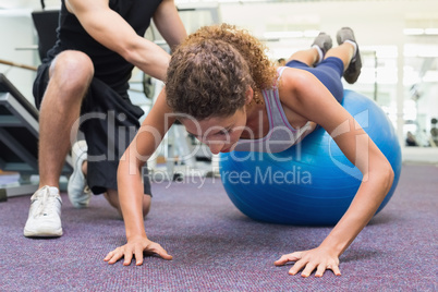 Trainer helping client workout on exercise ball