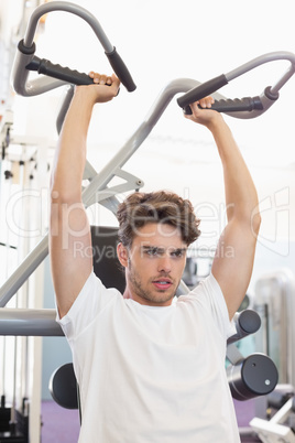 Fit focused man using weights machine for arms