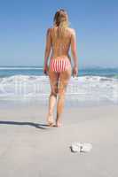 Fit woman in bikini walking towards the sea