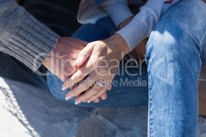 Couple holding hands sitting on sand