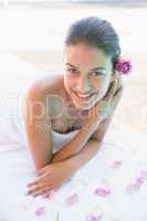 Smiling brunette lying on towel with rose petals