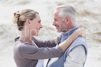 Happy hugging couple on the beach looking at each other