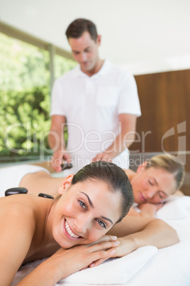 Pretty friends lying on massage tables getting hot stone massage