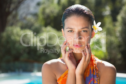 Brunette in sarong looking at camera by the pool
