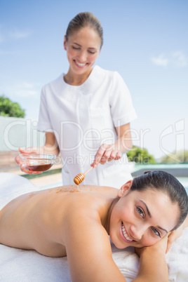 Happy brunette getting a honey beauty treatment poolside