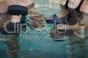 Man and woman holding foam dumbbells in the pool