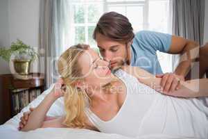 Cute couple relaxing on bed about to kiss