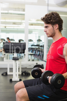 Fit man holding heavy black dumbbells