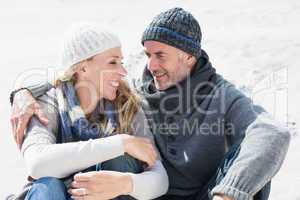 Attractive couple smiling at each other on the beach in warm clo