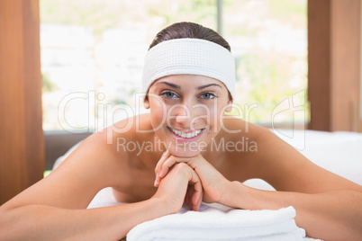 Beautiful smiling brunette lying on massage table