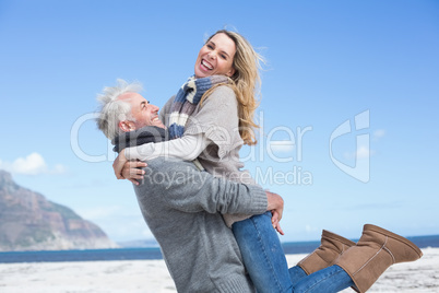 Smiling couple having fun on the beach in warm clothing