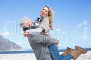 Smiling couple having fun on the beach in warm clothing