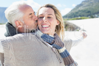 Carefree couple standing on the beach in warm clothing