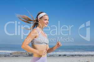 Sporty smiling blonde jogging on the beach