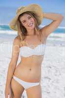 Beautiful happy blonde on the beach in white bikini and sunhat