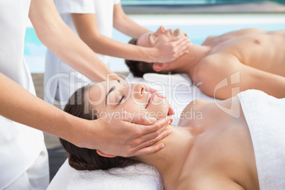 Content couple enjoying head massages poolside