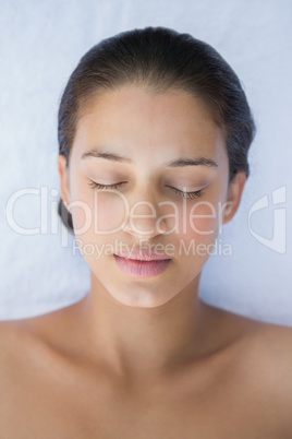 Peaceful brunette lying with eyes closed on a towel