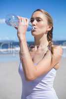 Focused fit blonde drinking water on the beach